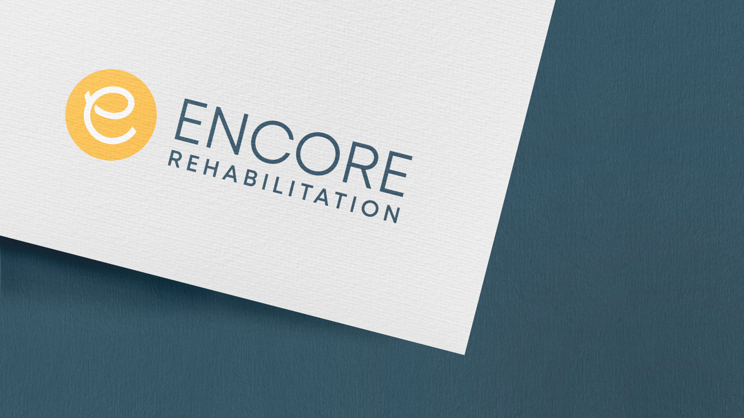 Encore-Logo-copy-scaled The letter "e" is a yellow circle next to the words "Encore Rehabilitation" on the corner of a sheet of paper