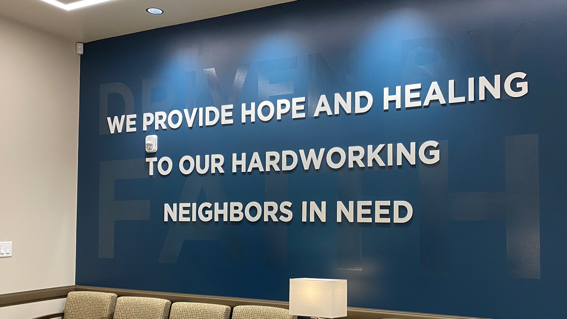 Faith-Family-Images-Resized-1 Blue office wall with text "We provide hope and healing to our hardworking neighbors in need"