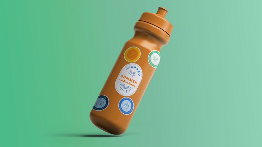 A titled orange water bottle with an assortment of Jarrard stickers on a green background