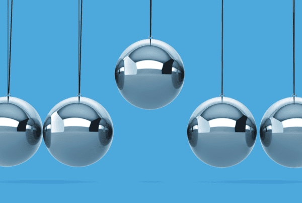 Newtons Cradle Balance Balls with the center ball lifted higher than the rest on a blue background